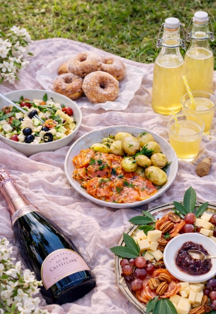 Vappupiknik puistossa: kreikkalainen pastasalaatti, perunasalaatti, aperolsuolattu lohi, tapasvati, vappumunkit, kullankeltainen sima ja kuohuviini.