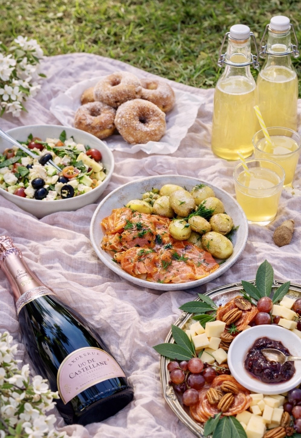 Vappupiknik puistossa: kreikkalainen pastasalaatti, perunasalaatti, aperolsuolattu lohi, tapasvati, vappumunkit, kullankeltainen sima ja kuohuviini.