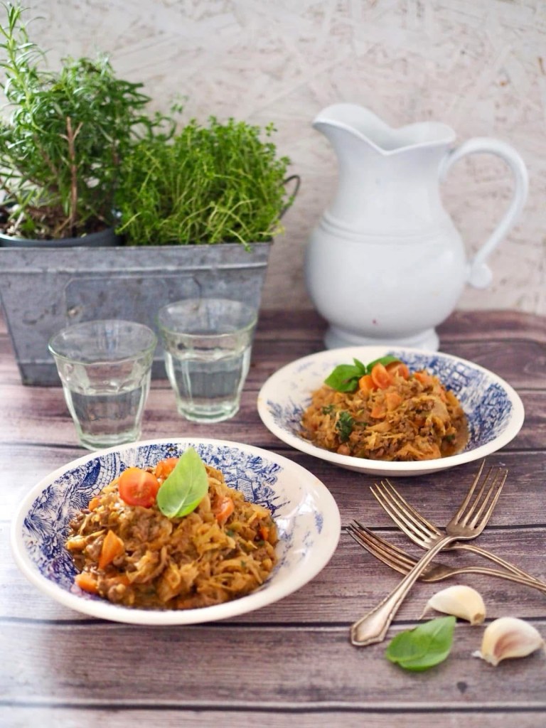 Varhaiskaalipata tarjoiltuna lautasilla, koristeltuna basilikalla ja kirsikkatomaateilla rustiikkisella pöydällä.